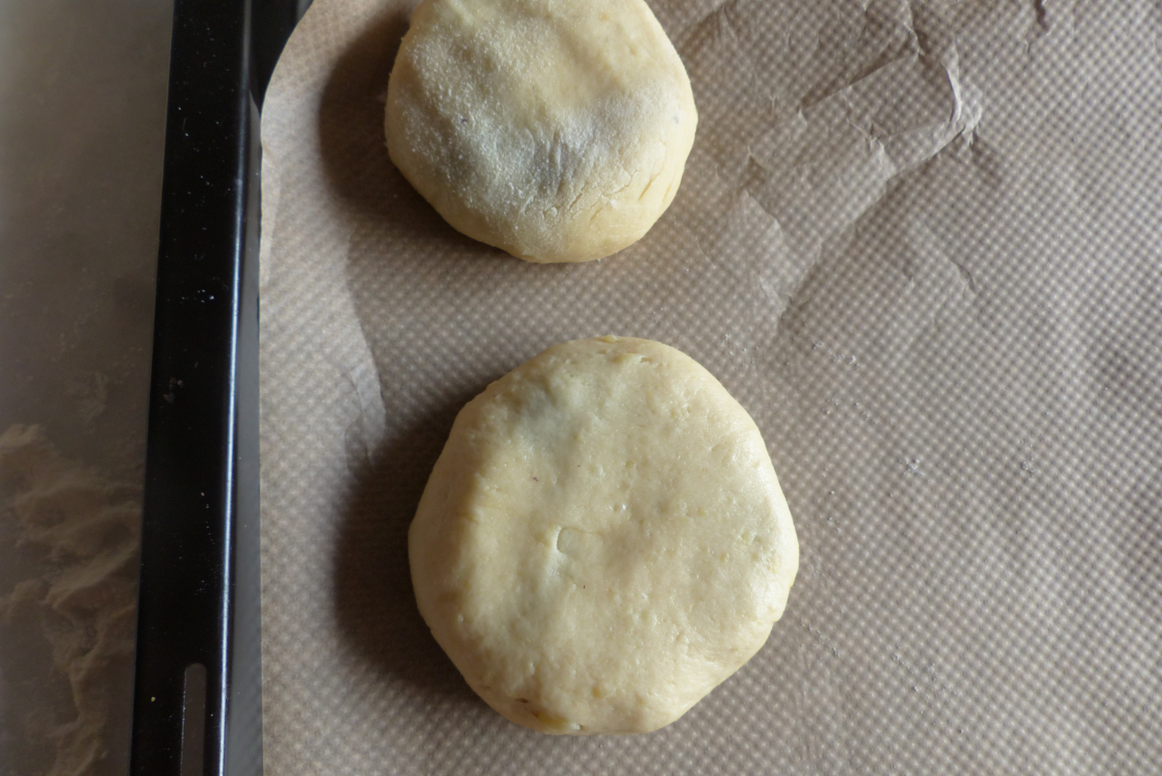 <p>2 Zelten-Teiglinge lagern mit ihrer Verschlussseite nach unten auf dem Backblech. </p>