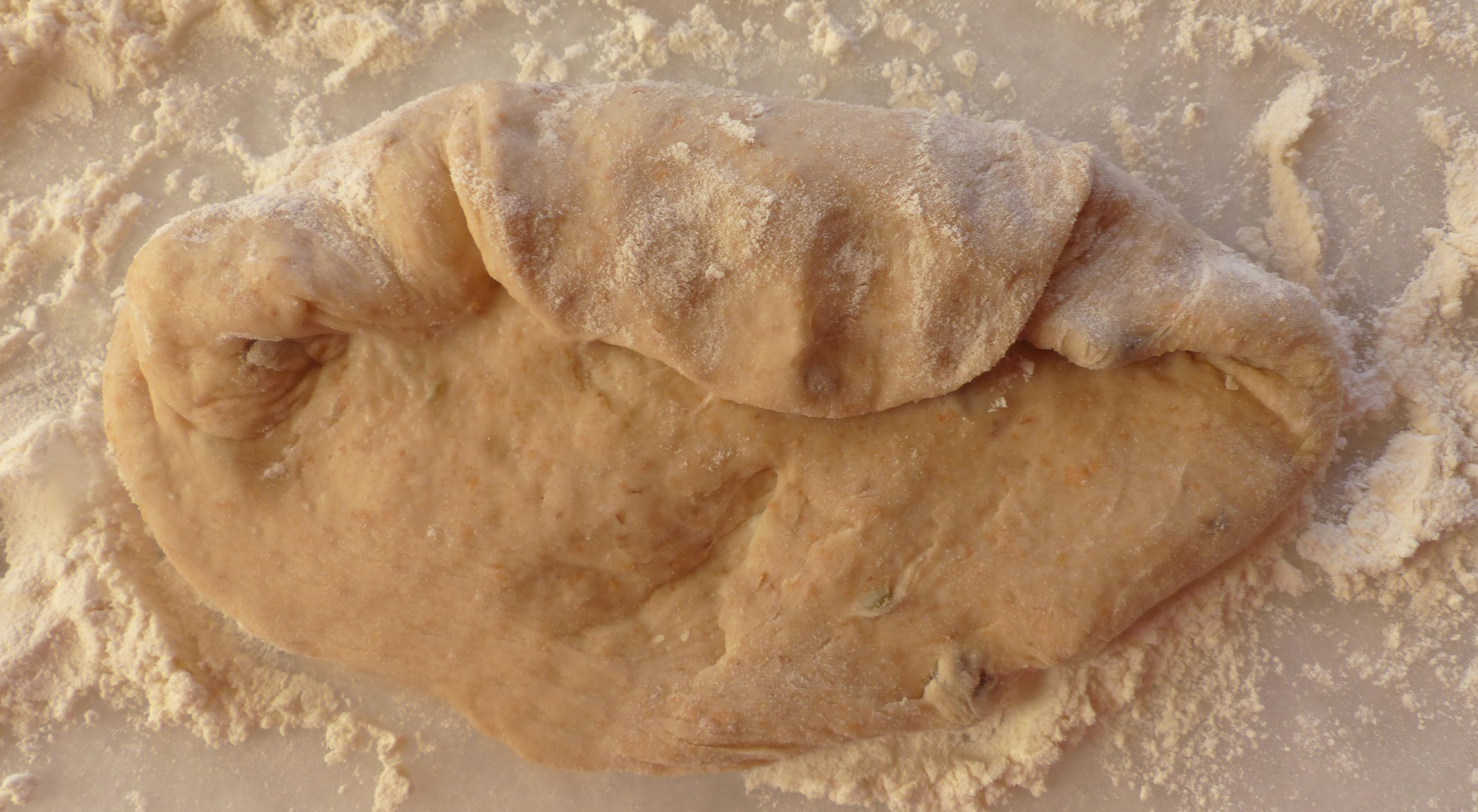 <p>​​​​​​​​​​​​​​Dann wird der Fladenrand von oben Mitte über die „Ohren“ zur Mittellinie geklappt.</p>