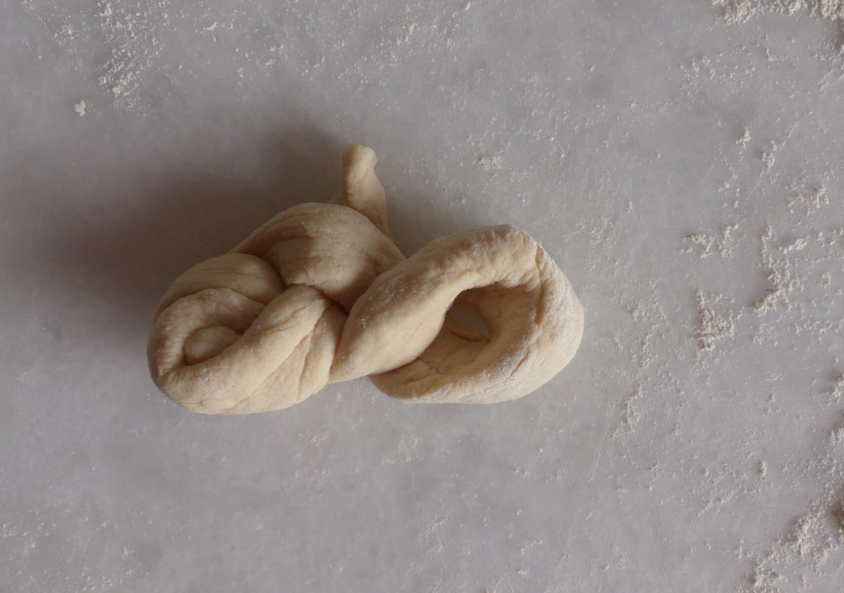 <p>Einstrangzopf - 5. Schritt:<strong> </strong></p><p>Die Schlaufe wurde nach  o b e n  gedreht. Man erkennt die Form einer liegenden Acht.</p>